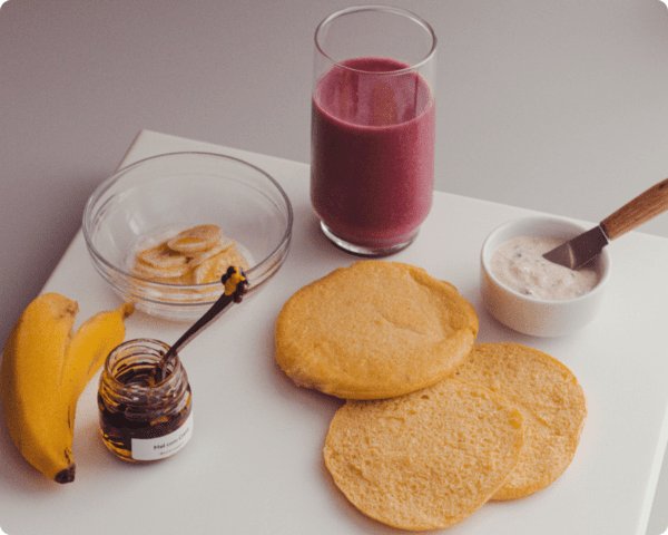 sugestão de café da manhã ou café da tarde com pão de grão de bico, mel, banana, patê saudável e suco natural de açaí